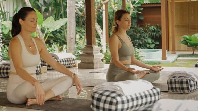 Group of women practicing yoga outdoors at the Ubud Goddess Retreat, surrounded by lush greenery and tranquil nature