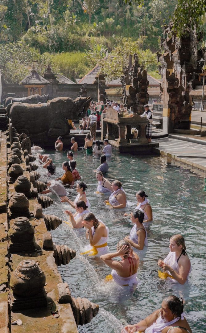 Tirta Empul Holy Spring during a healing retreat in Bali, with participants engaged in a purification ceremony at the sacred water temple.