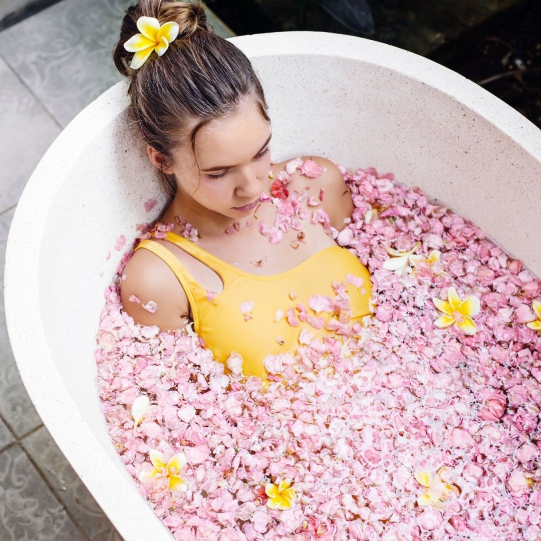 Vibrant pink and yellow floral bath setup at Goddess Retreats, featuring a peaceful, luxurious atmosphere with flowers and spa elements for relaxation and rejuvenation.