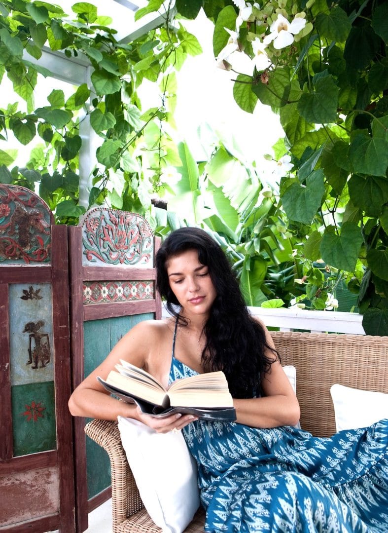Relaxing wellness moment at a Goddess Retreat, featuring a woman reading a book in a serene setting